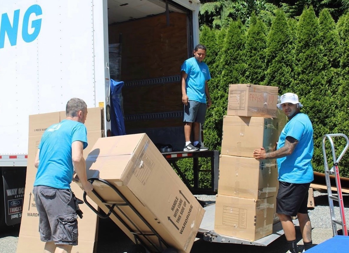 Movers loading office furniture and equipment into a truck in Toronto
